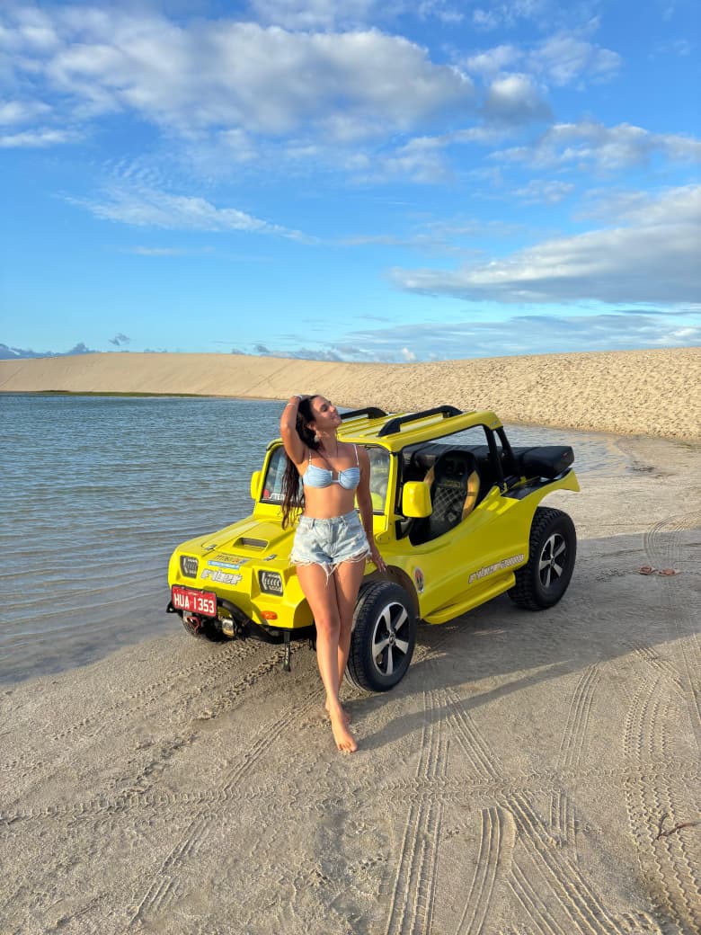 Turista junto ao buggy amarelo na beira da Lagoa do Paraíso em Jericoacoara