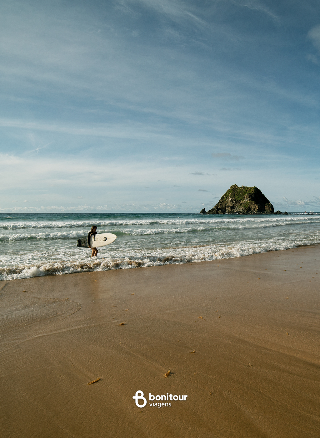 Vista de longe de praia de Fernando de Noronha com surfista na beira da água