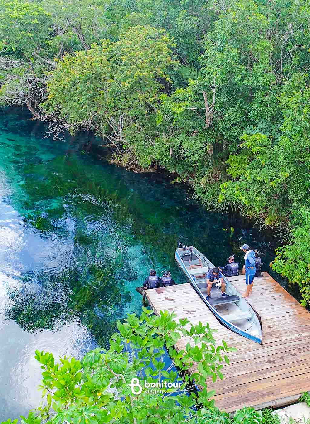Pessoas e barco em cima de deck de madeira, às margens do Rio Sucuri.