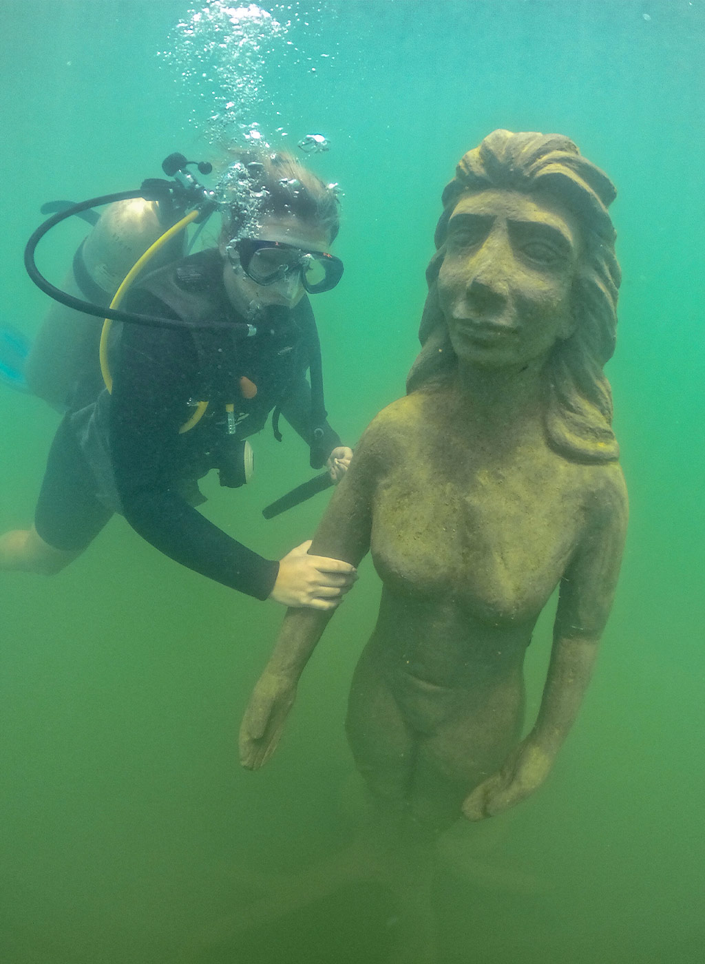 Mergulhador se divertindo em baixo da água com estátua do Museu Subaquático