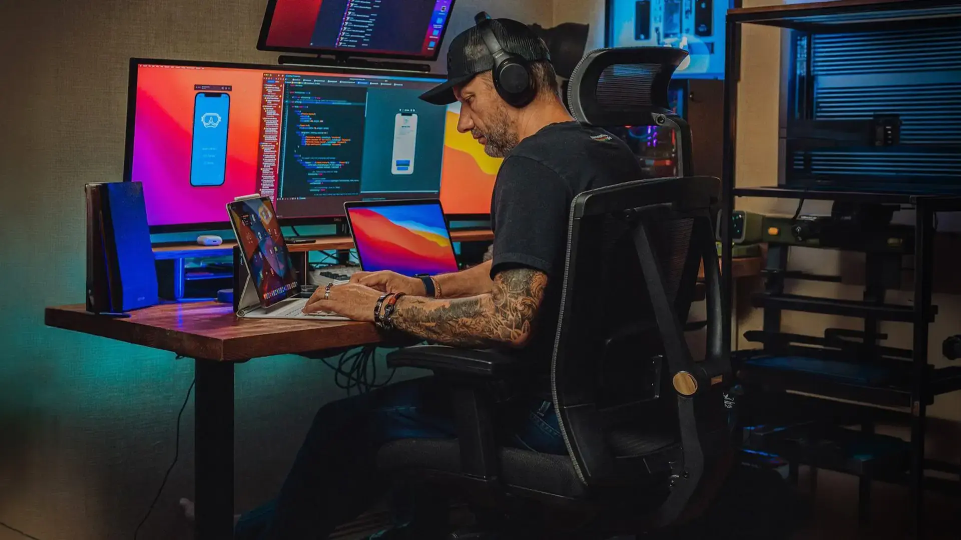 A person seated in an Autonomous ErgoChair at a multi-monitor desk setup