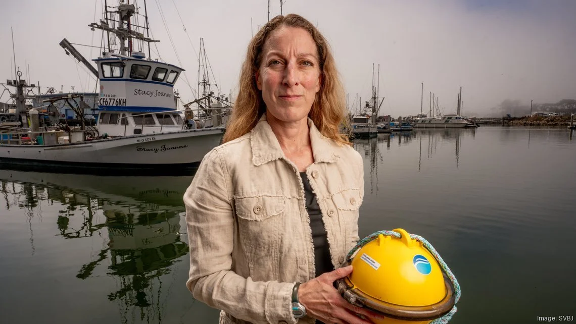 Kortney Opshaug holding a yellow Smart Buoy in a harbor full of fishing boats