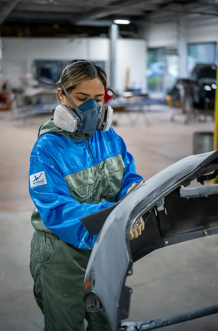 Technician refinishing a vehicle in a paint booth