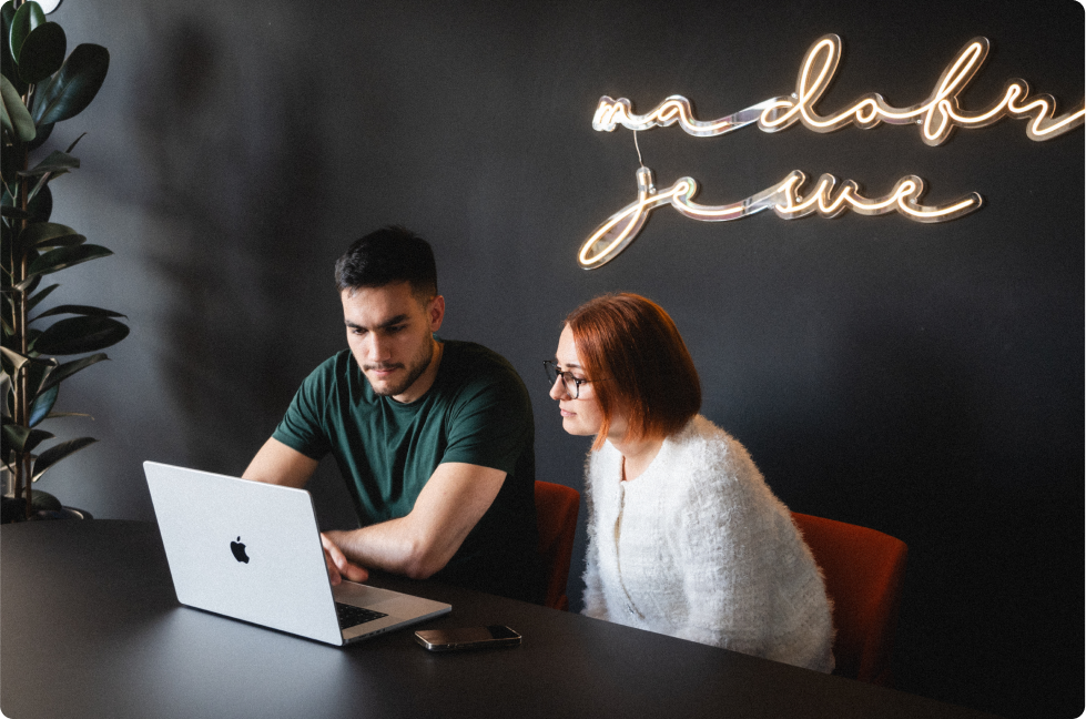 Two members of TP Accurate's product team reviewing work on a laptop