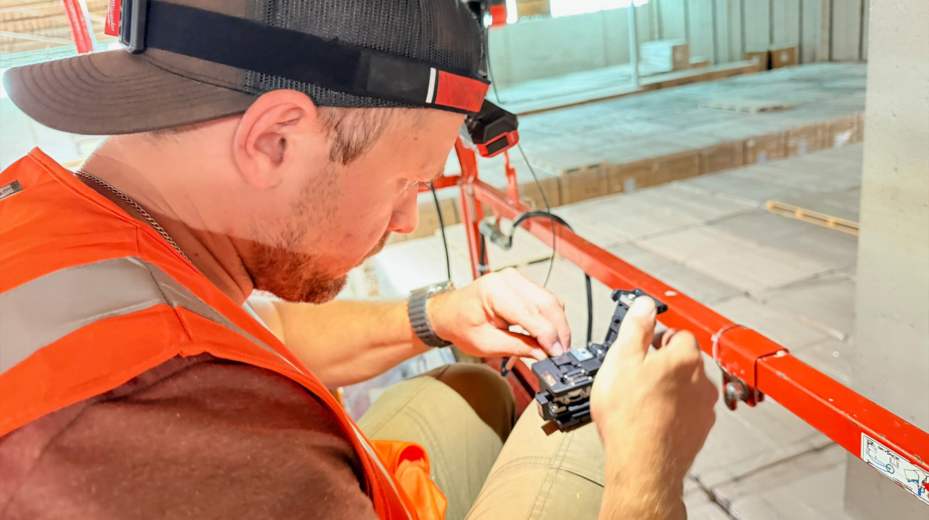 Close-up of a low-voltage technician wearing safety gear preparing glass fiber strands for molecular fusion splicing.