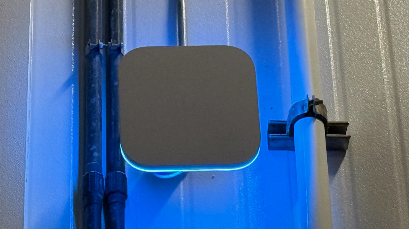 UniFi access point with bright blue LED light mounted on a corrugated metal wall panel