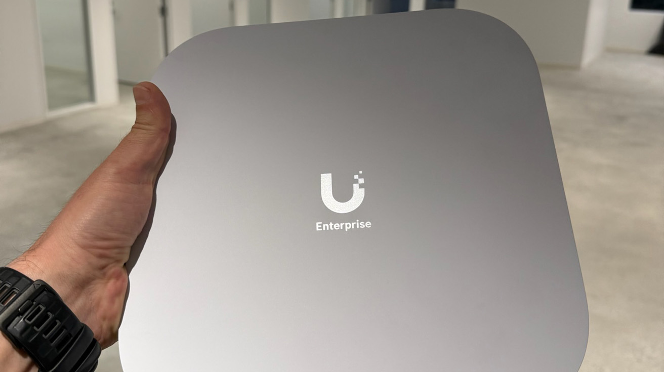 Ceiling mounted UniFi access point with glowing blue LED indicator and professional cable management conduit