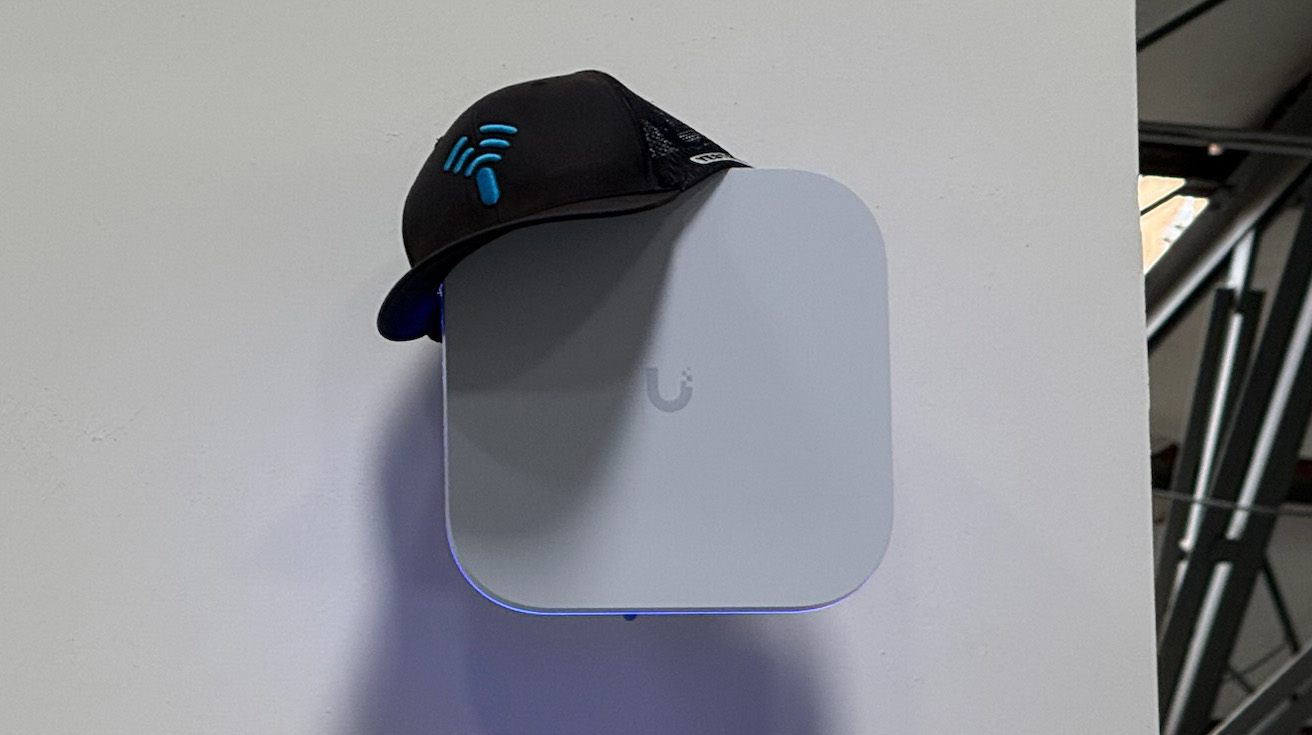 UniFi access point mounted on a clean white wall inside an office or commercial building