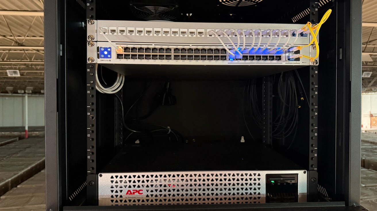 A neatly organized intermediate distribution frame rack featuring a UniFi Pro Max switch connected via yellow single-mode fiber optic patch cables.