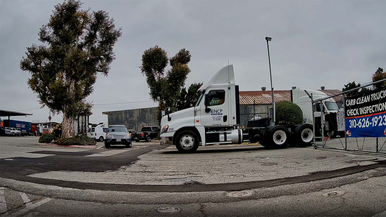 Side view of a tractor-trailer passing through automated entrance gates for AI metadata tagging