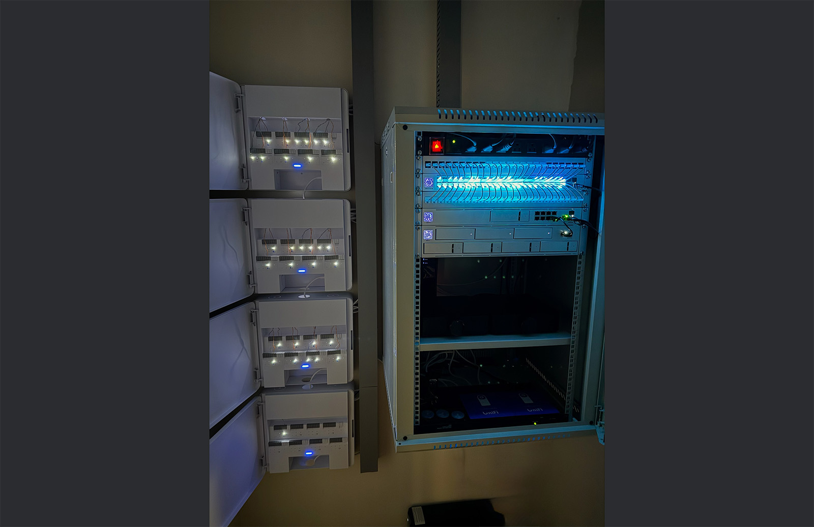 A neatly organized telecommunications rack featuring UniFi routing hardware alongside perfectly managed door access control hubs.