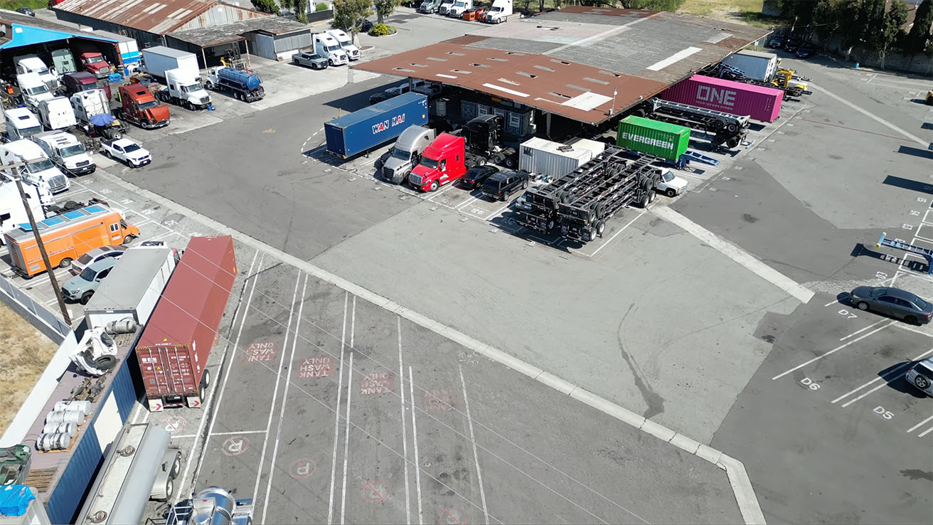 High-angle view of multi-tenant logistics yard with automated entry gates and LPR