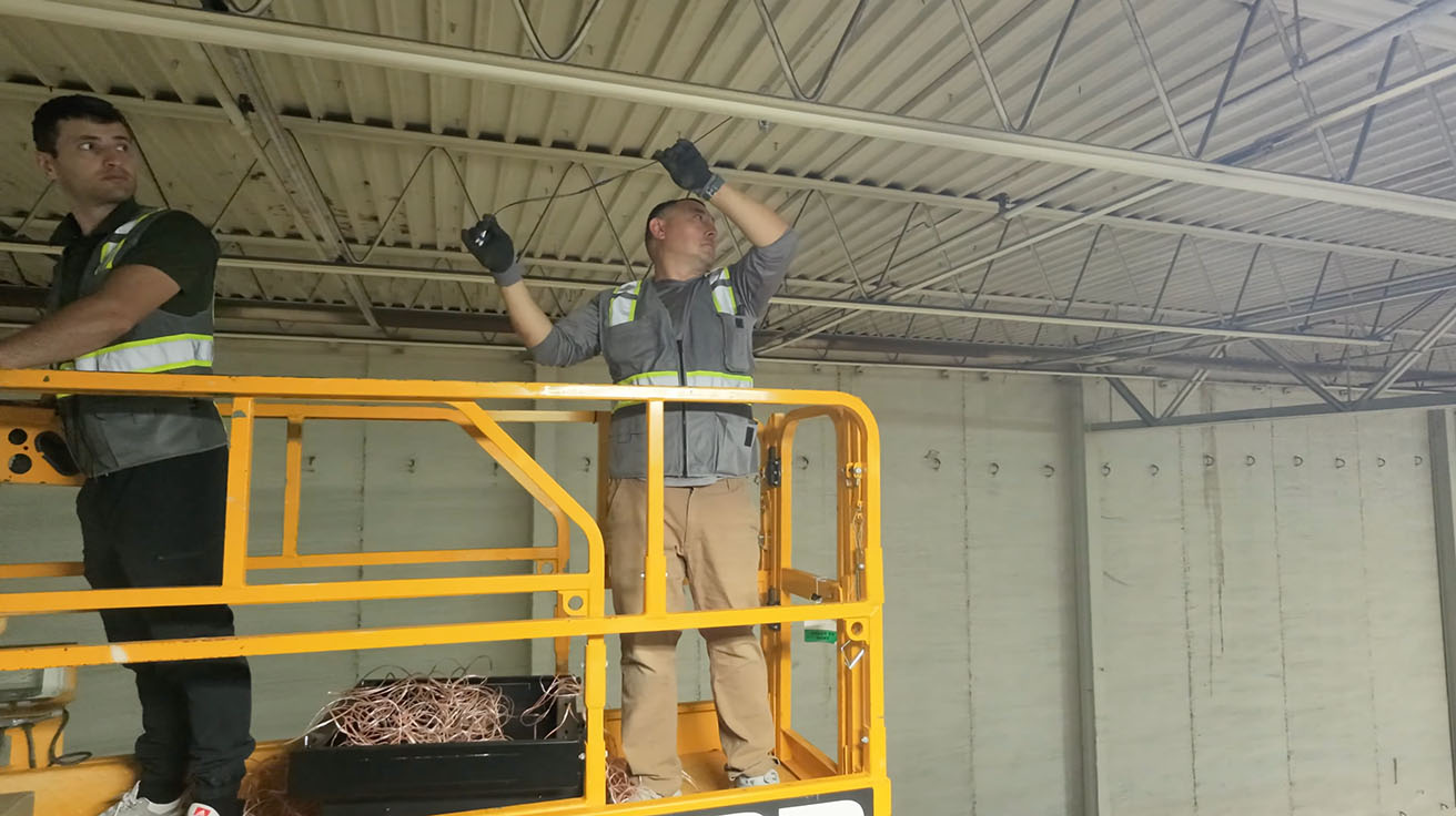 Technical team operating a scissor lift to install high-altitude structured cabling