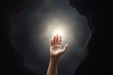 Hand reaching for light out of darkness, hope for financial recovery.