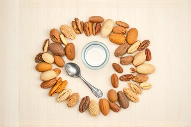 Variety of raw nuts with measuring spoon and water