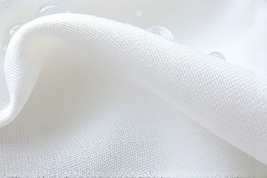 Close-up of fabric fibers being cleaned by water droplets, showing gentle care.