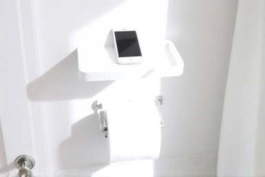Modern bathroom shelf holding smartphone above toilet paper holder