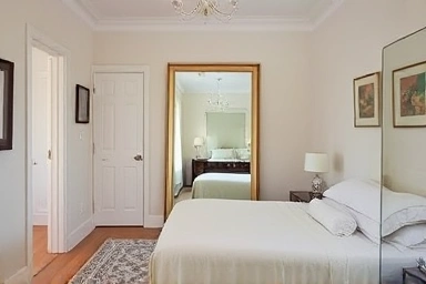 Spacious bedroom achieved with a full-length mirror.