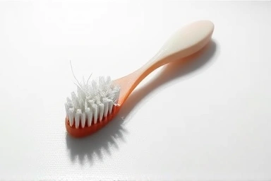 Worn-out toothbrush with frayed bristles on a white surface.