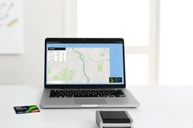 Hi-Pass device, laptop, road trip map, credit card, modern desk.