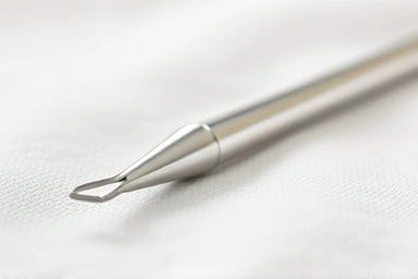 Clean stainless steel acne extractor tool on white cloth
