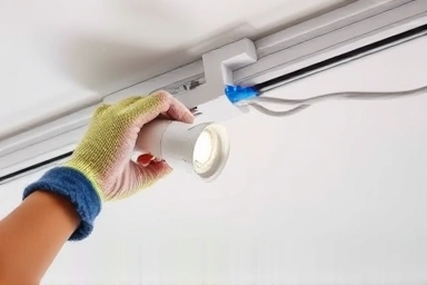 Hands performing DIY track light installation with tools.