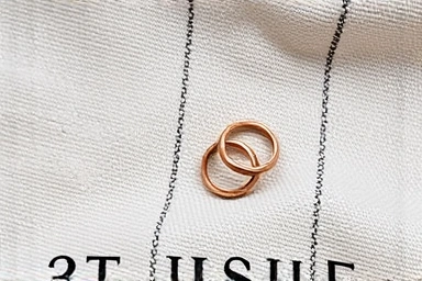 Minimalist and engraved pinky rings arranged on textured fabric.