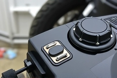 Close-up of motorcycle battery, tire, and fuel cap during winter storage.