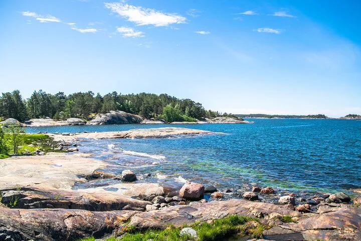 Rocky coastline with blue water and forested islands.