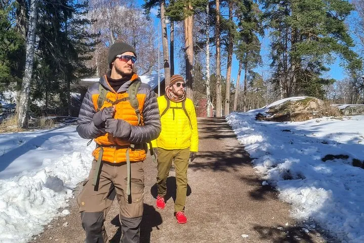 Two men hiking snowy forest path.