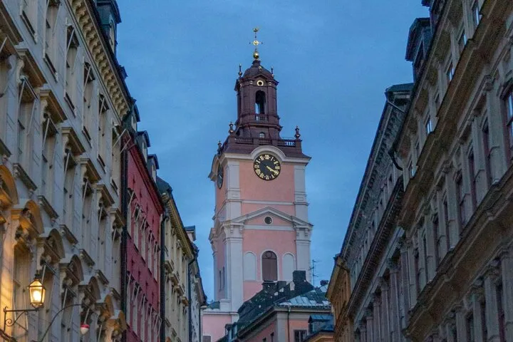 Pink clock tower framed by historic city buildings.