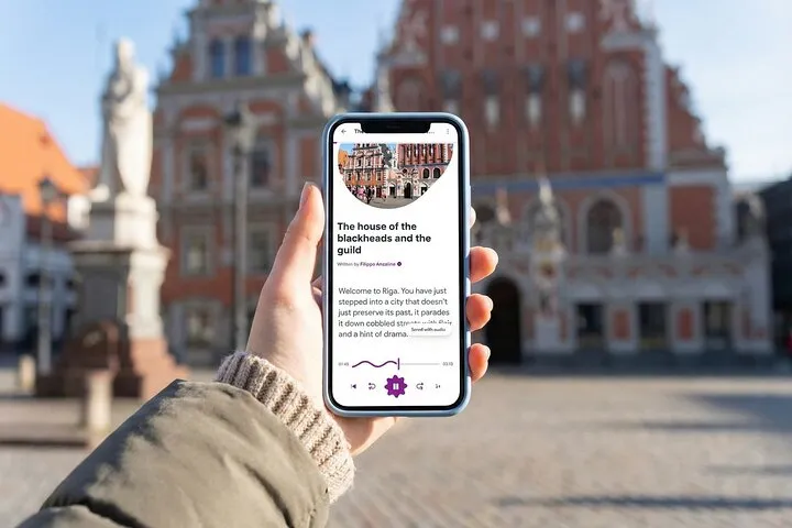 Hand holding smartphone with Riga audio guide app.