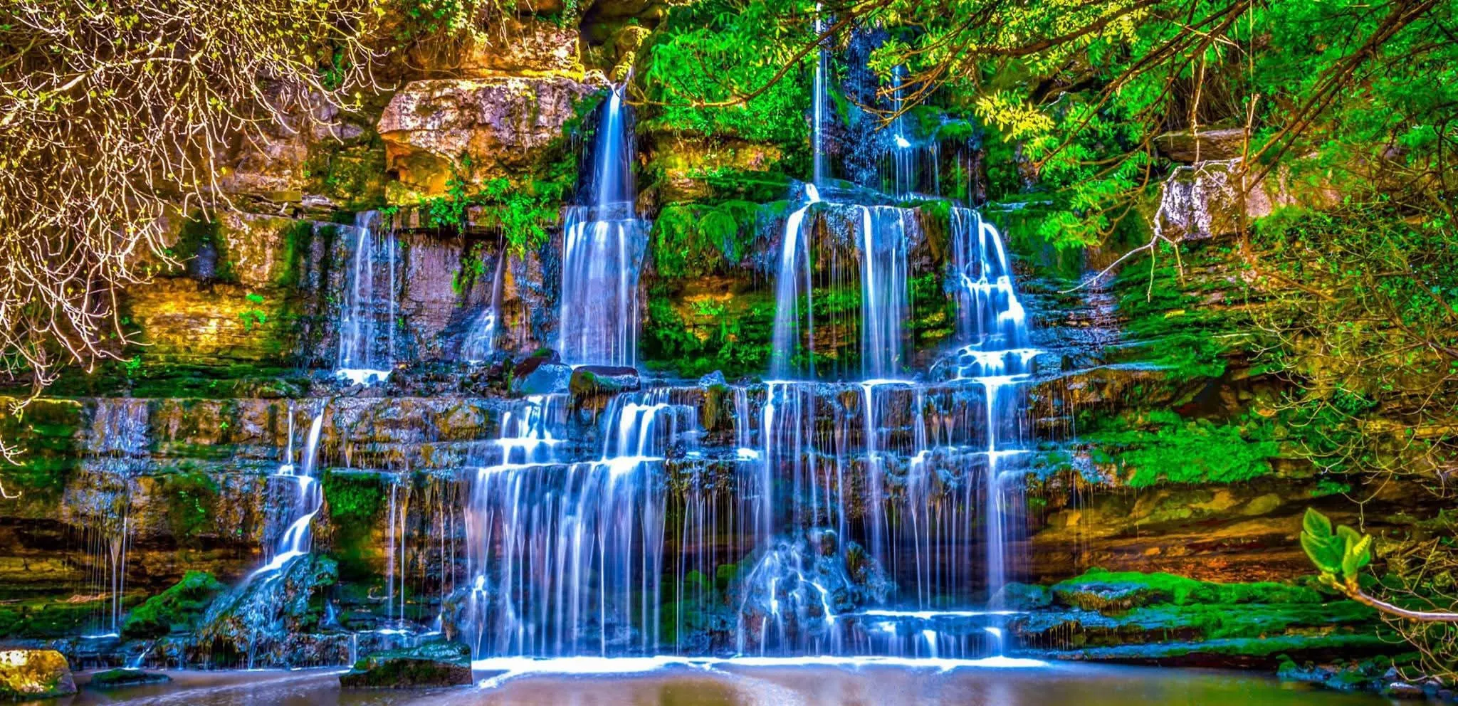Majestic tiered waterfall, lush green forest.