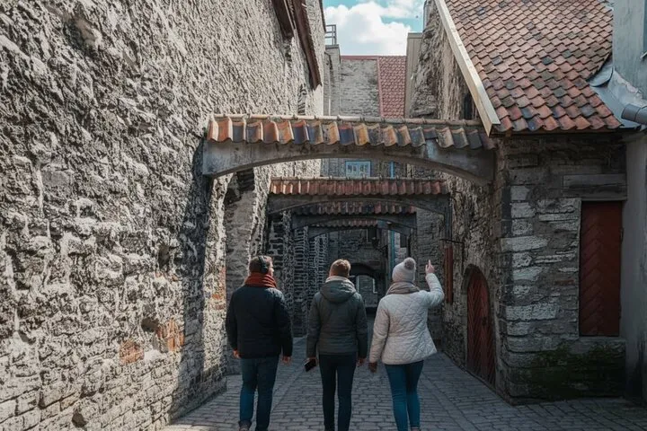 Tourists walking historic stone alley with arches.