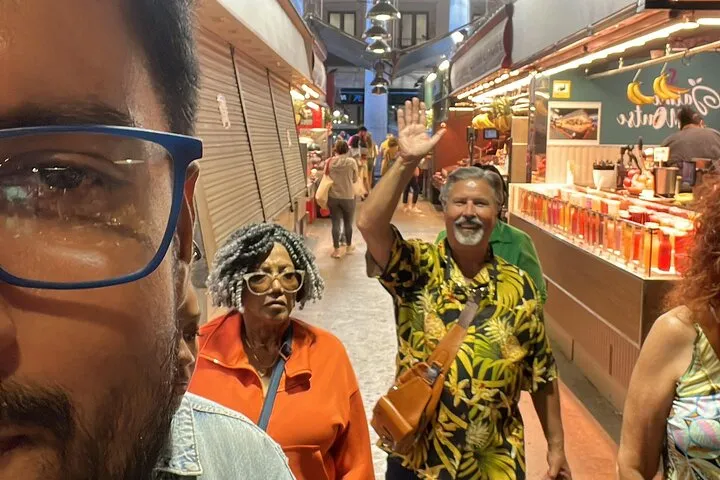 Smiling man waving in a vibrant market.