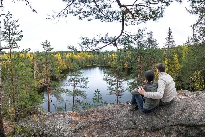 Couple on rock overlooking autumn lake forest.