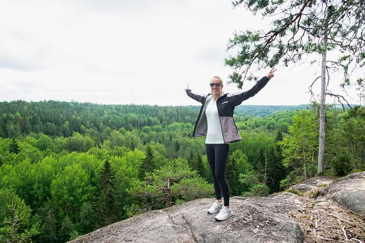 Woman hiker on rock with panoramic forest view.
