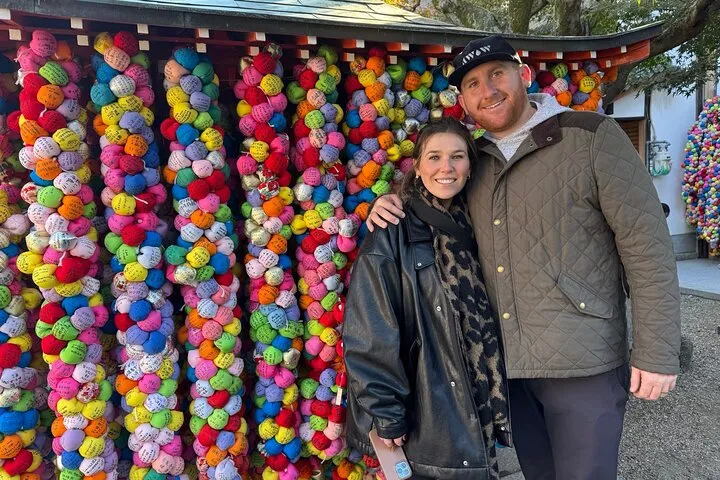 Smiling couple in front of colorful omikuji.
