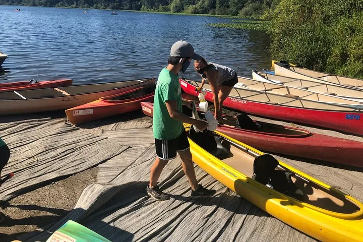 People cleaning canoes by the lake.