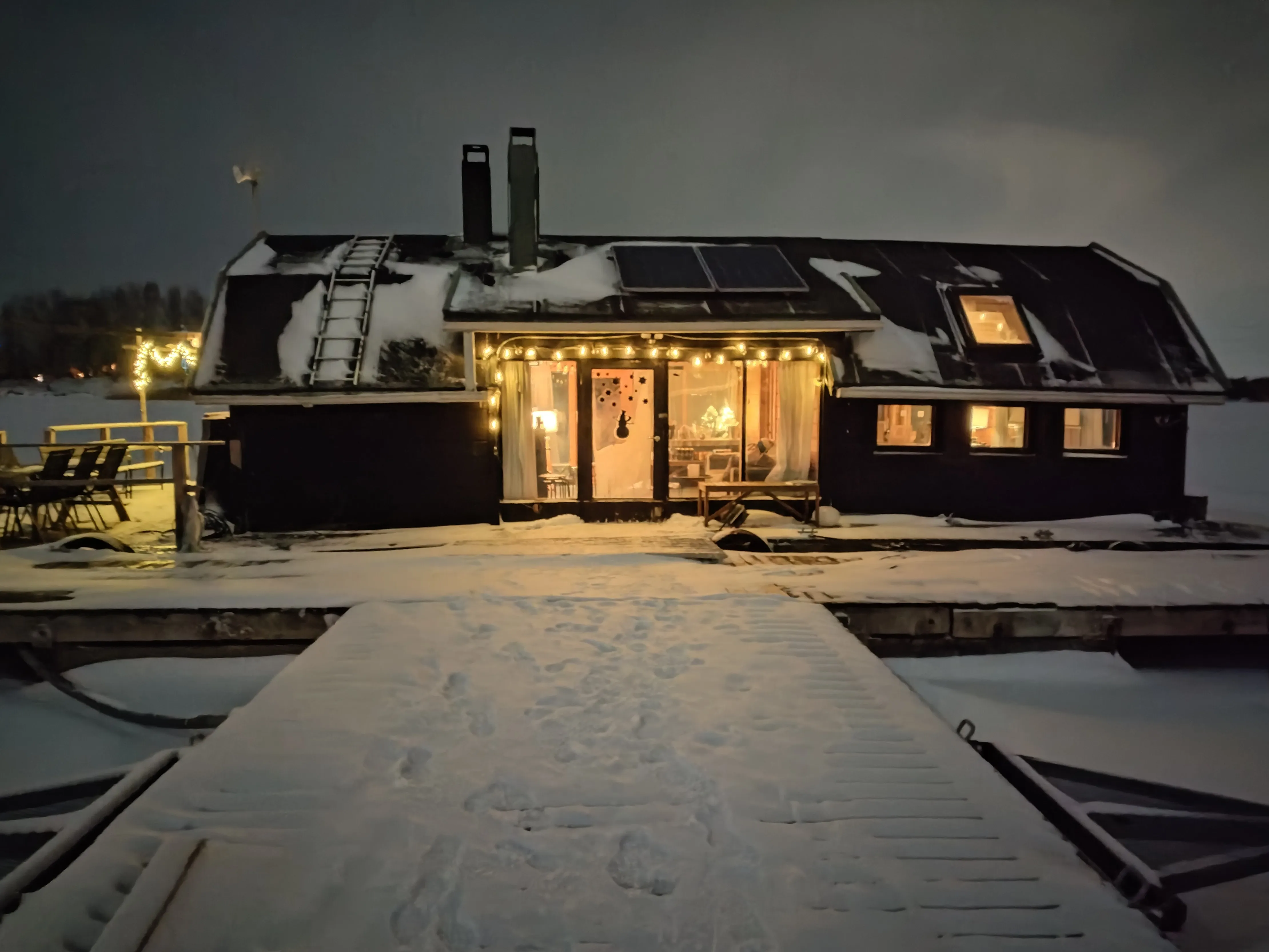 Cozy houseboat on snowy dock, winter night.