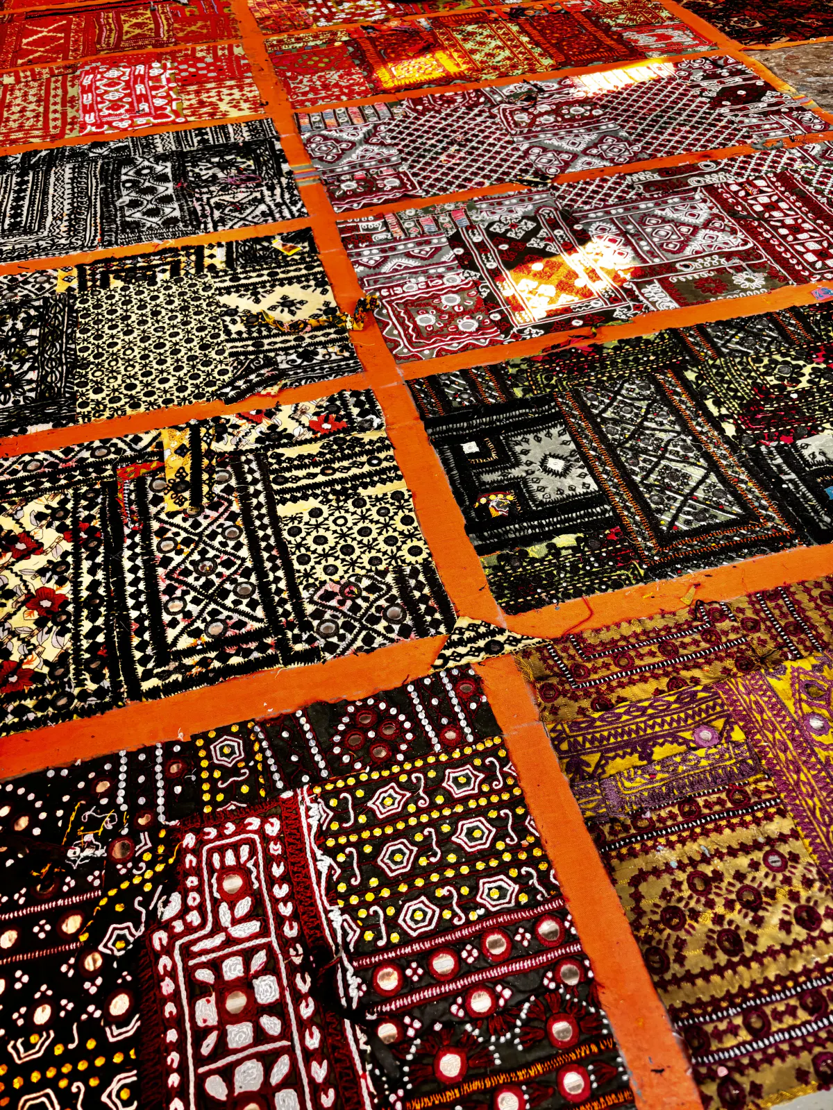 Embroidered sample panels laid out in rows across a floor, spread open to be chosen from