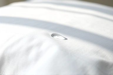 Clean white pillowcase with dewdrop, symbolizing freshness.