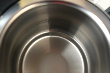 Pristine interior of a stainless steel electric kettle, free of stains.