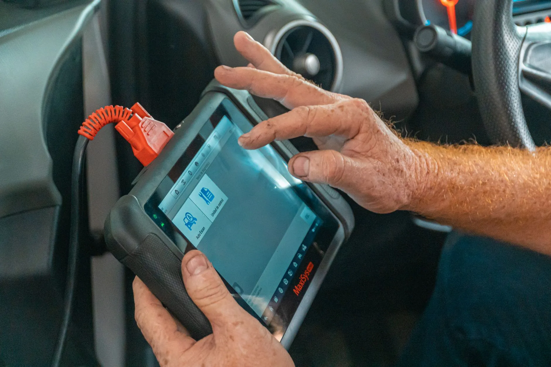 a mechanic using a diagnostic scan tool on a car outside a home