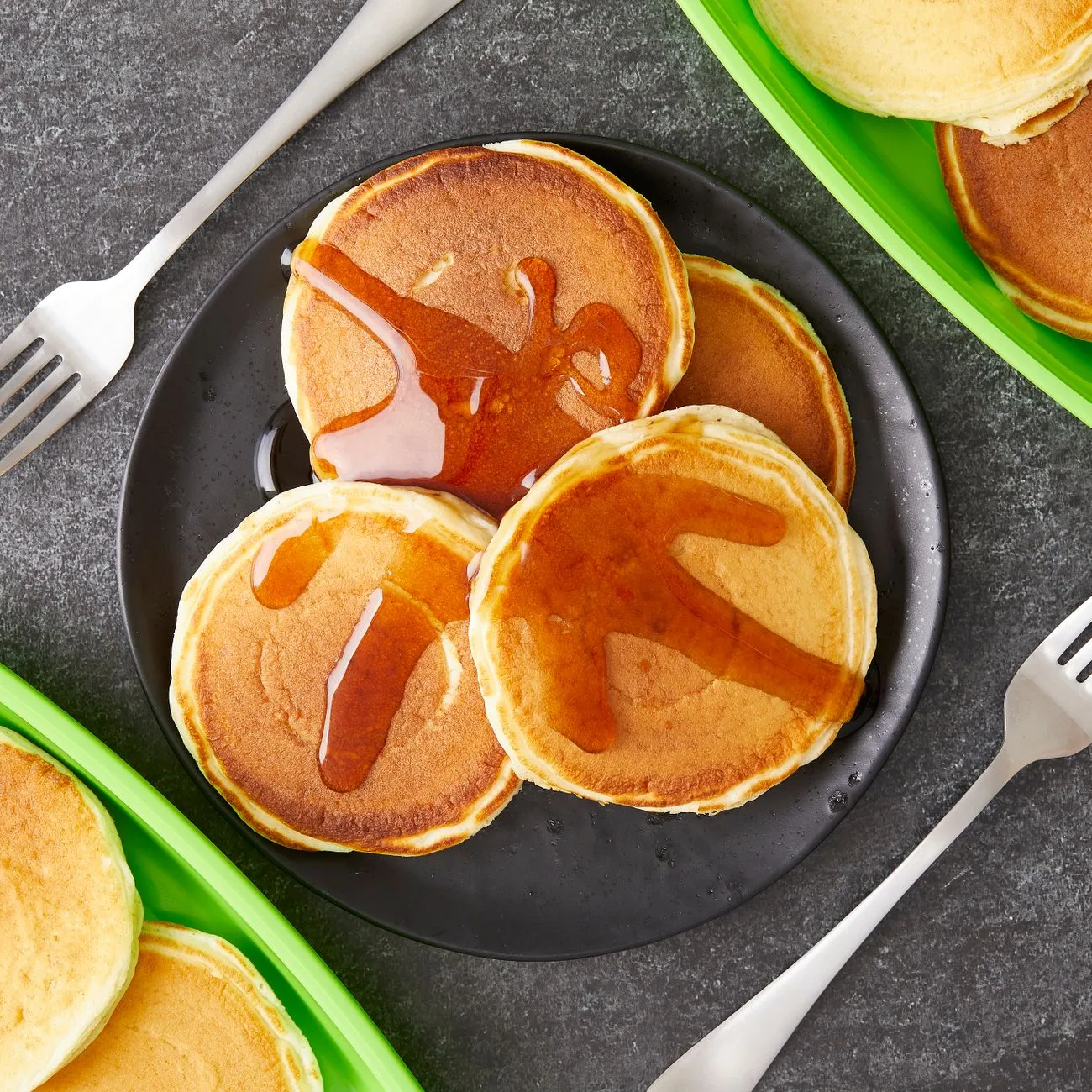 pancakes on a dark plate with syrup poured over