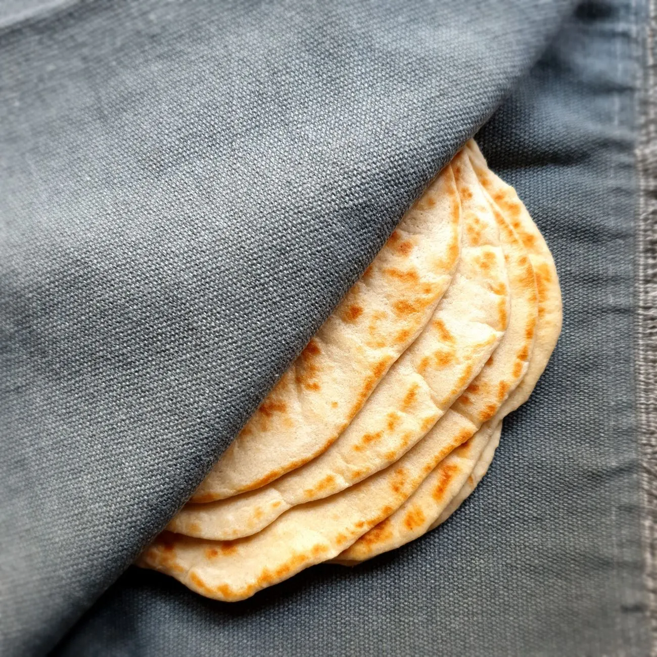 a stack of fresh corn tortillas wrapped in a cloth