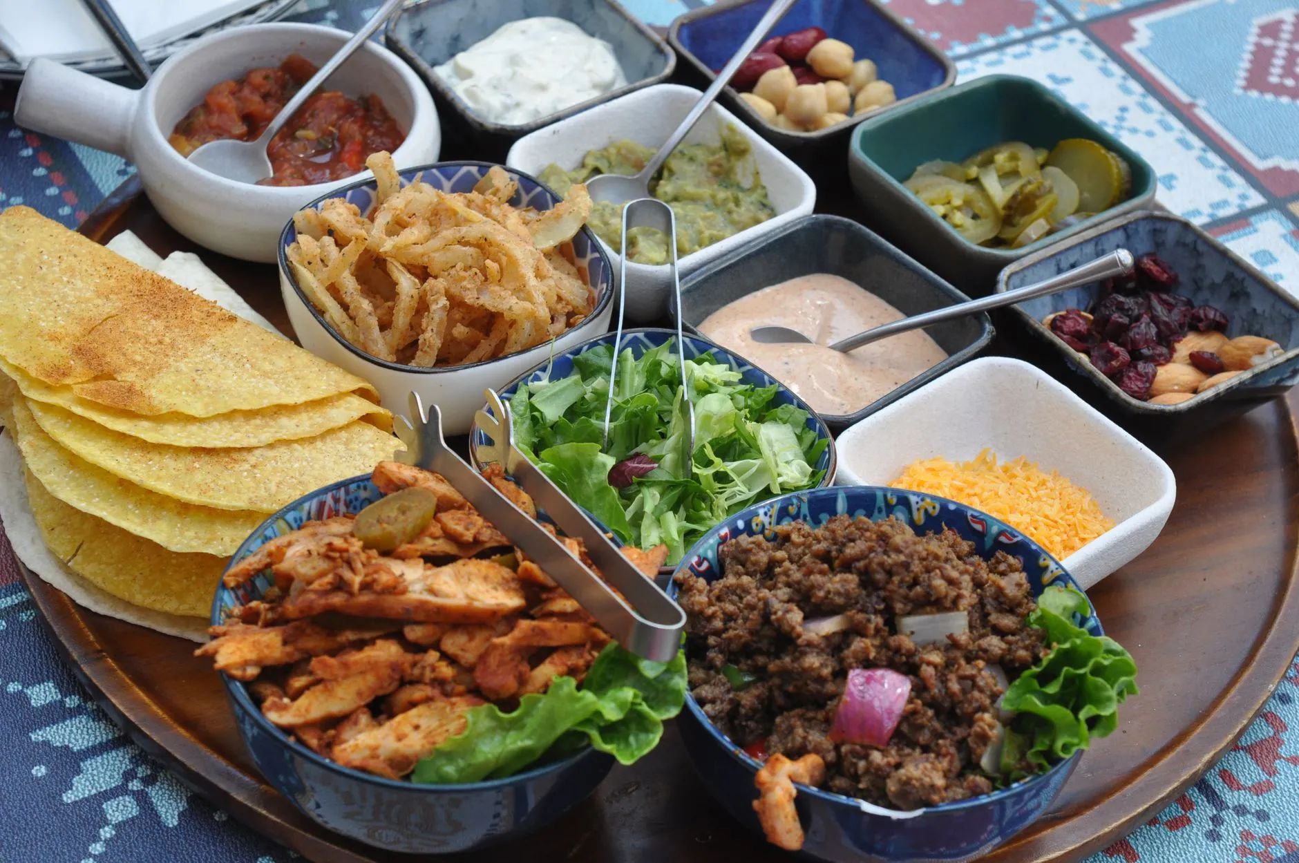 a taco bar with bowls of toppings and tortillas