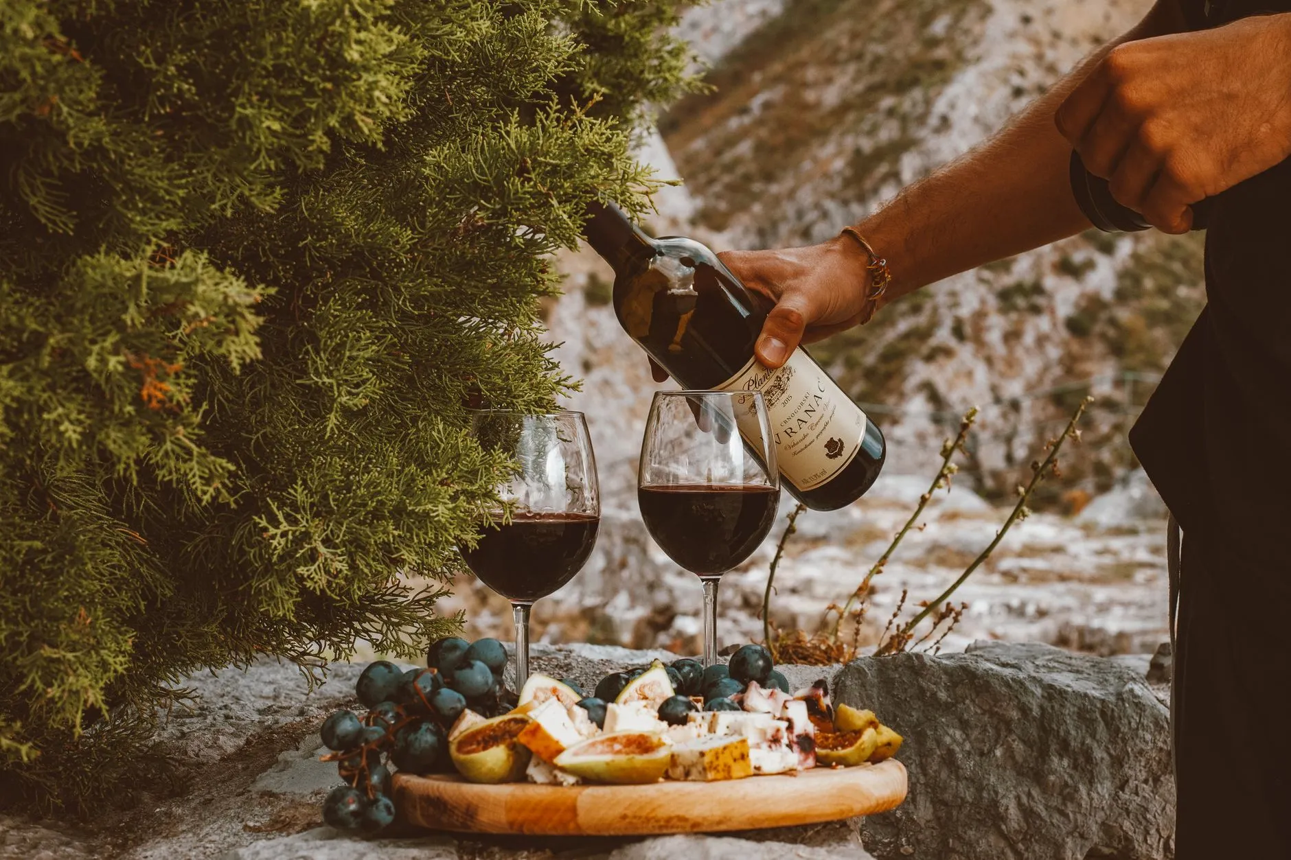servers pouring wine at an outdoor vineyard dinner table