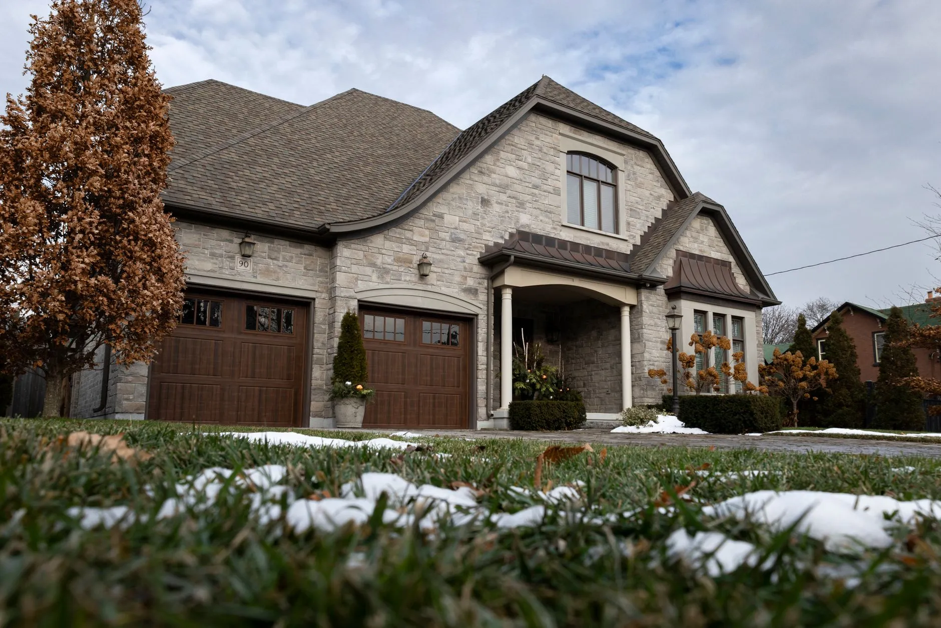 A two-storey stone house with an arched entry and a landscaped drive