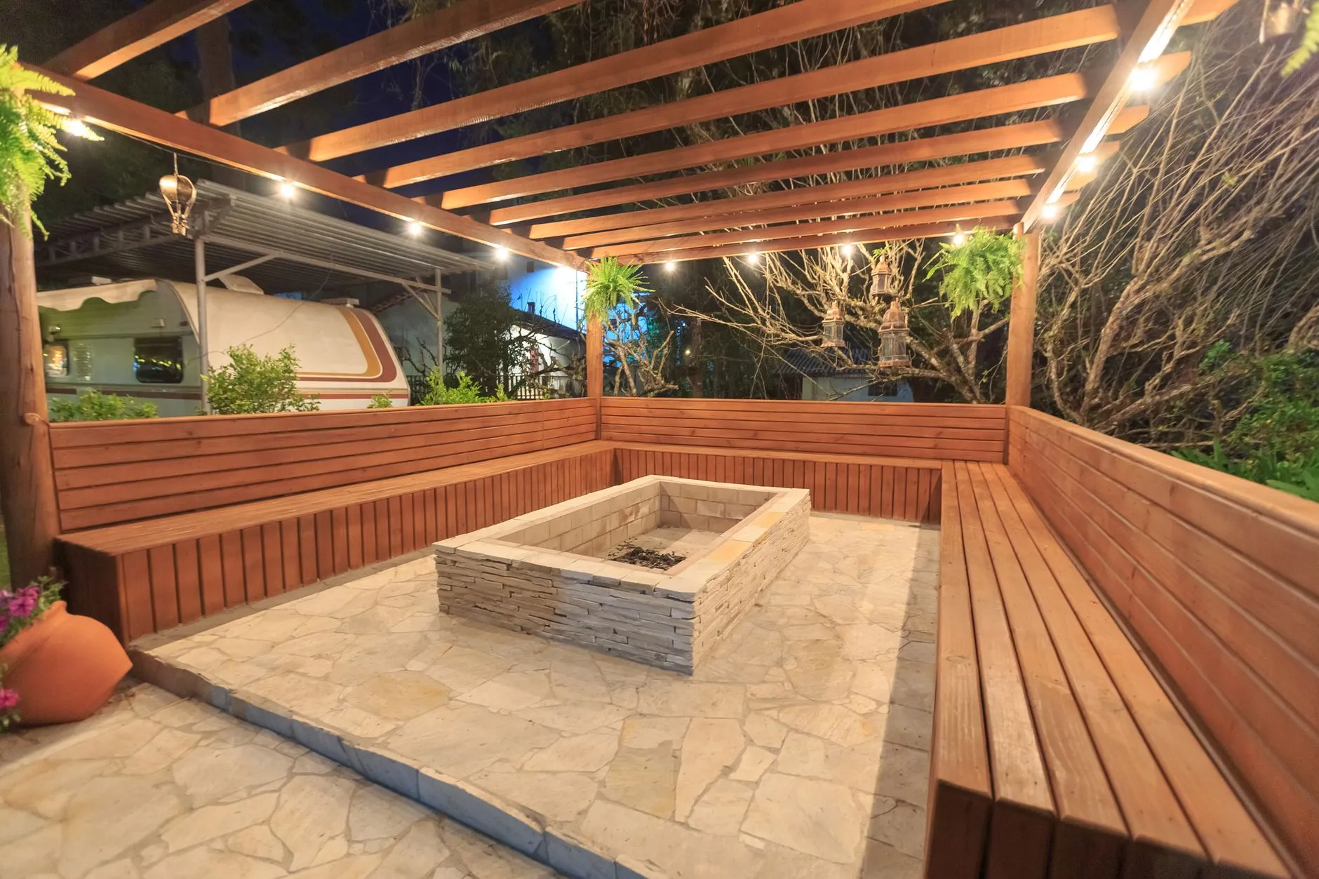 A timber deck with a built-in perimeter bench wrapping a stone fire feature
